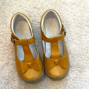 L’amour tan Mary Jane shoes with Velcro buckle and bow.